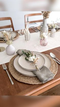 the table is set with plates, silverware and flowers