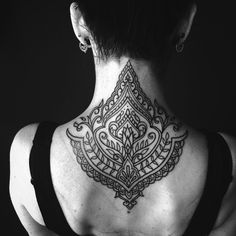 the back of a woman's neck with an intricate tattoo design on her chest