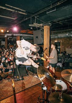 a band playing in front of an audience at a rock concert with one man on the drums