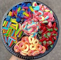 a person holding up a plate full of colorful candies and pretzel rings