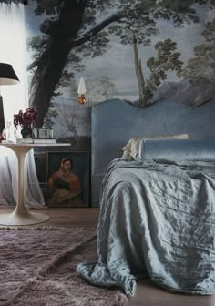 a bedroom with a painting on the wall next to a bed and nightstand in front of it