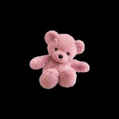 a pink teddy bear sitting in the dark