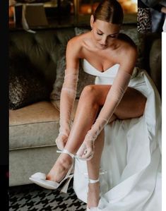 a woman sitting on top of a couch wearing white shoes and holding her leg in the air