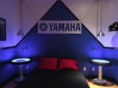 a bed with red pillows and blue lights in a room that has a yamaha sign on the wall