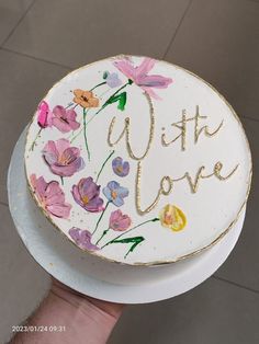 a hand holding a cake decorated with flowers and the words, with love on it