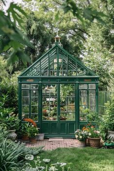 a small green house surrounded by greenery and flowers