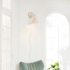 a living room with white walls and a green chair next to a potted plant