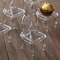 four clear chairs sitting on top of a wooden floor next to a cupcake in a glass container