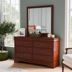 a bedroom scene with focus on the dresser, mirror and plant in the foreground