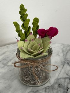 a glass jar filled with flowers on top of a marble table covered in grass and twine