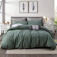 a bed with green comforter and pillows in a room next to two pictures on the wall