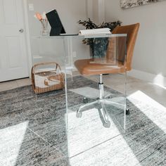 a glass desk with a laptop on it in the middle of a room next to a basket