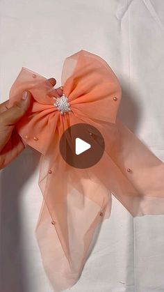 someone is holding an orange bow on top of a white sheet with the video below it