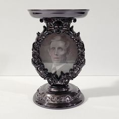 an ornate silver candle holder with a portrait on it