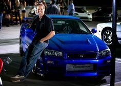 a man leaning on the hood of a blue car