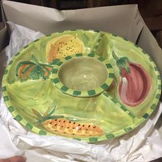 a green and yellow plate sitting on top of a cardboard box next to a bowl