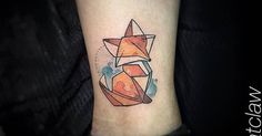 a small tattoo on the ankle of a woman with an orange and blue fox design