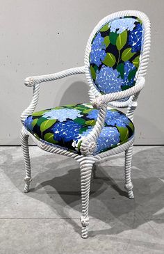 a white wicker chair with blue and green floral upholstered seat padding