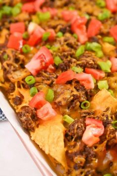 a casserole dish with beef, cheese and tomatoes on top is ready to be eaten