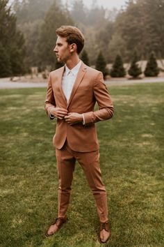 a man in a brown suit standing on grass