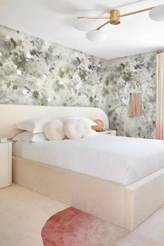 a large bed sitting in a bedroom next to a wall with flowers painted on it