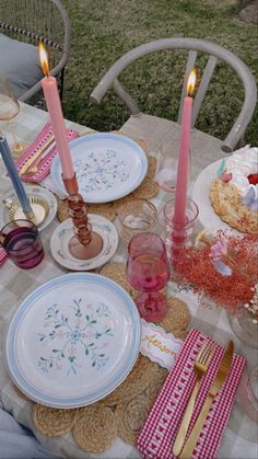 a table set with plates, candles and napkins for a party or picnic outside