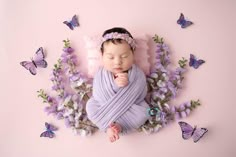 a baby wrapped in purple is surrounded by butterflies