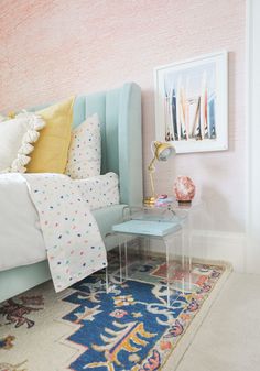 a bed room with a neatly made bed next to a painting on the wall and a rug