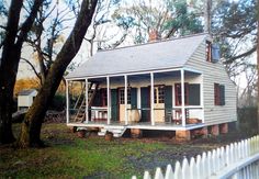 a small white house sitting next to a tree