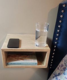 a wooden shelf with a glass and book on it