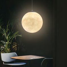 a round light hanging over a table in a dark room