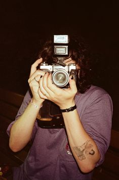 a woman holding up a camera to take a photo in the dark with her hands