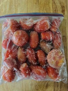 a plastic bag filled with fruit sitting on top of a wooden table