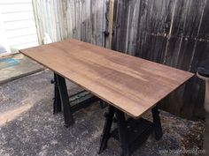 a large wooden table sitting on top of a cement floor next to a fenced in area