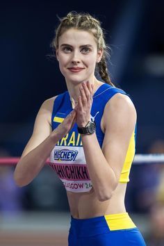 a woman standing on top of a track with her hands clasped in front of her face