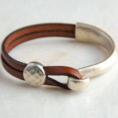 The beauty is in the simplicity. High quality components and expert craftmanship combine to make this popular - and gorgeous - leather wrap cuff bracelet for women and men a "must have" jewelry staple. Great for gift-giving. It's wearability and style suits both casual and dressy occasions.  This leather cuff features genuine leather, a sterling silver plated half hook clasp, and a hammered coin slider bead. This is my original design, first sold here on Etsy in 2017, and each item is handmade s Wrap Armband, Bracelets Boho, Leather Bracelets Women, Handmade Leather Bracelets, Rock Artists, Jewelry Staples, Men's Bracelets, Leather Cuff Bracelet, Leather Wristbands