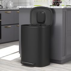 a black trash can sitting in the middle of a kitchen