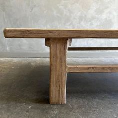 a wooden bench sitting on top of a cement floor