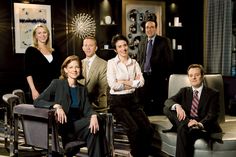 a group of people are posing for a photo in a living room with chairs and couches