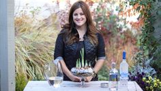 a woman sitting at a table holding a potted plant