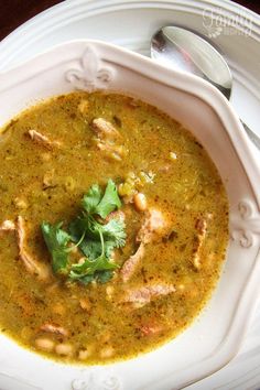 a white bowl filled with green soup and garnished with cilantro leaves