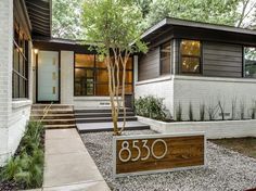 a house with a sign in front of it that says 350 on the sidewalk and trees