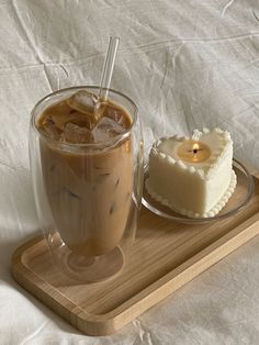 a cup of coffee next to a small cake on a wooden tray with white sheets