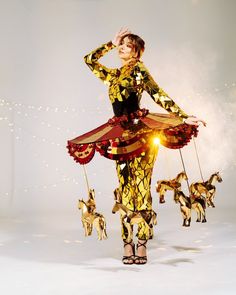 a woman is dressed in gold and black with horses on the string, while holding her hands behind her head