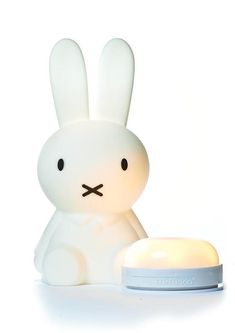 a white rabbit lamp sitting next to a light on top of a table with its eyes closed