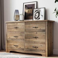 a wooden dresser sitting next to a window with pictures on the top and bottom shelf