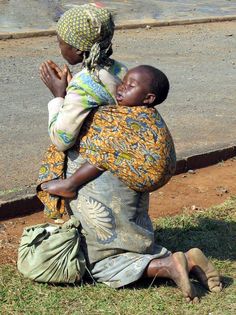 a woman sitting on the ground holding a baby