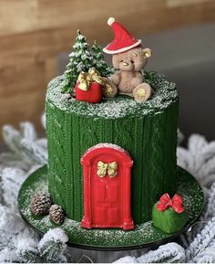 a christmas cake with a teddy bear sitting on it's top and decorations around the base