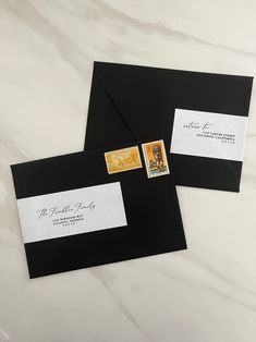 two envelopes with stamps on them sitting on top of a marble countertop next to each other