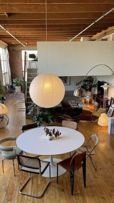 a living room filled with furniture and a white table surrounded by chairs on top of hard wood flooring